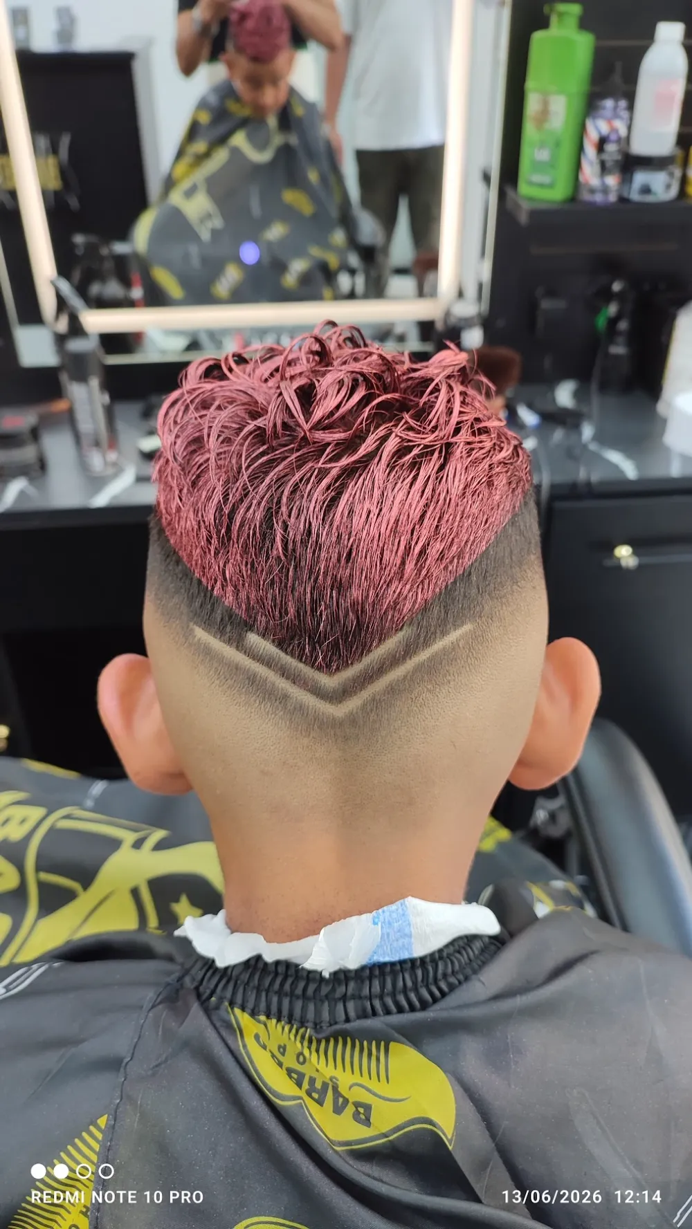 Niño de espaldas con el pelo pintado de rojo y un dibujo marcado a cuchilla