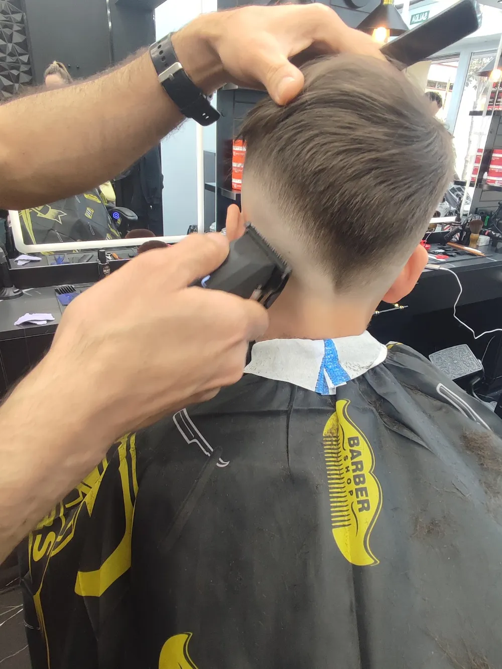 Niño en el sillón mientras el barbero le pasa la máquina por la nuca